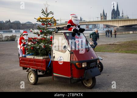 Piaggio Ape with Christmas tree, members of the Vespa scooter club RheinSchalter Koeln dressed as Santas gather on Deutzer Werft before a ride through Stock Photo