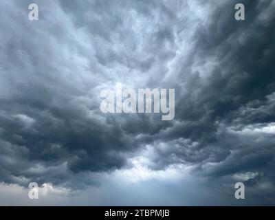 An ominous sky of dark clouds is seen rolling in over an expansive grassy plain, creating a dramatic atmosphere Stock Photo