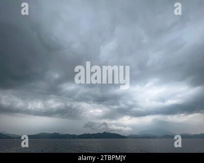 An ominous sky of dark clouds is seen rolling in over an expansive grassy plain, creating a dramatic atmosphere Stock Photo