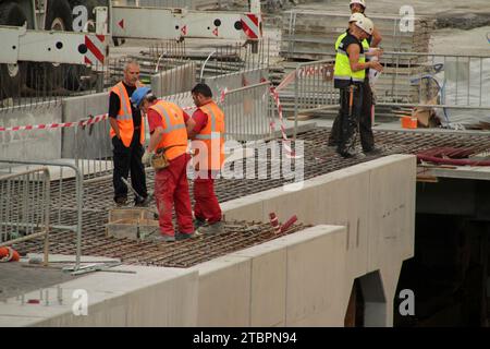 A group of professionals wearing construction vests and orange safety vests, standing together in a construction site Stock Photo