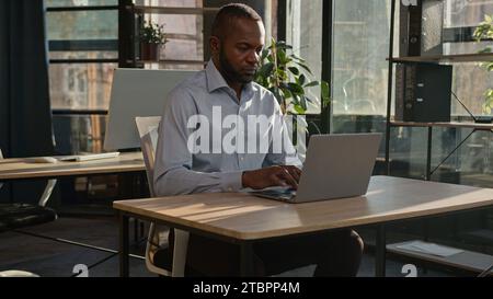 African american mature businessman working business project typing email on laptop in sunny office pensive focused man male entrepreneur middle-aged Stock Photo