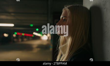Side view portrait Caucasian businesswoman female girl in underground parking garage in shopping center waiting taxi car. Close up serious sad Stock Photo