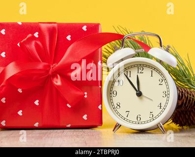 Alarm clock and stack of red gift boxes on yellow background Stock Photo