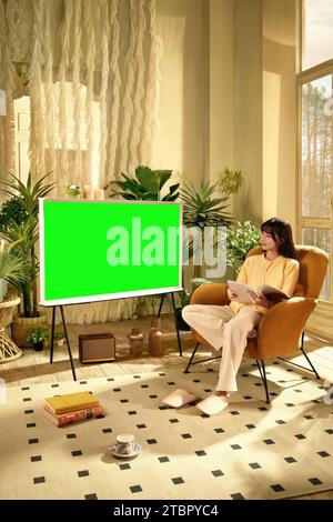 People are watching and enjoying next to the TV, monitor with green screen Stock Photo