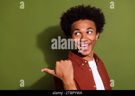 Photo of good mood cheerful man with afro hair dressed brown shirt look directing at sale empty space isolated on khaki color background Stock Photo