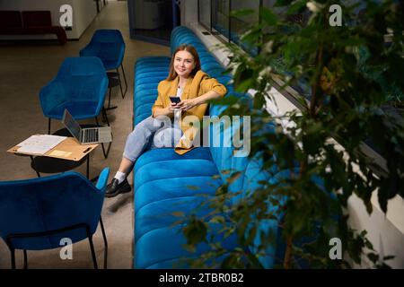 Female freelancer sits with a phone in her hands Stock Photo