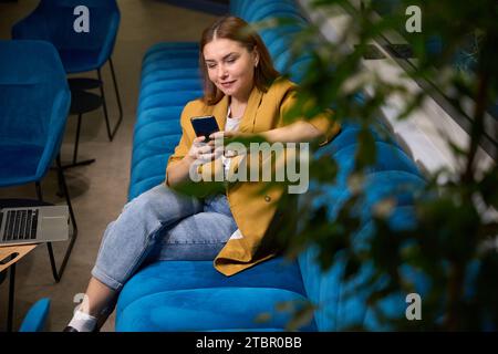 Woman manager sits with a phone in her hands Stock Photo