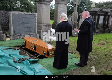 Glasgow Scotland Greek Orthodox Funeral at Glasgow Necropolis - Priest Reading the Committal Prayers at Graveside with Funeral Director holding Olive Stock Photo