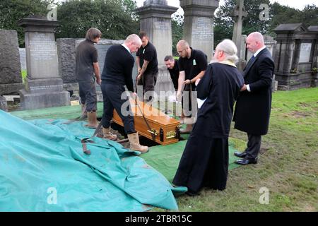 Glasgow Scotland Greek Orthodox Funeral at Glasgow Necropolis - Priest Performing the Committal Service as the Coffin is Manually Lowered into the Gra Stock Photo