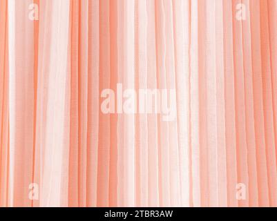 Abstract background of soft pleats of peach color quilled fabric. Festive background for design. A copy space. Color of the Year 2024 Peach Fuzz. Stock Photo