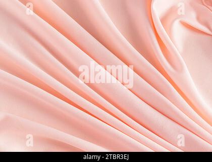 Stylish festive peach blossom background. Background image of factory fabric. Gorgeous soft pleats. A copy space. Color of the Year 2024 Peach Fuzz Stock Photo