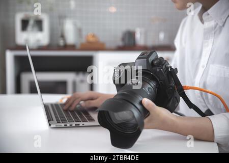 Female photographer, blogger reviewing photos taken with her camera using a laptop Stock Photo