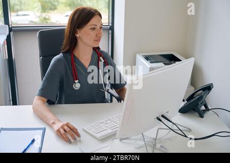 Concentrated female doctor using computer in her office Stock Photo