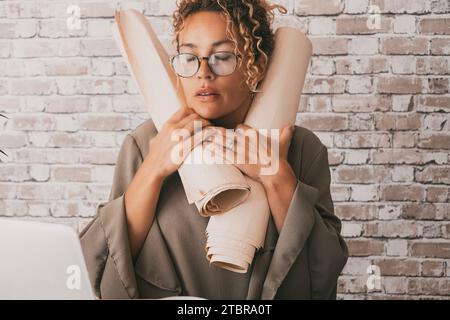 One businesswoman stressed at the desk alone holding design paper documents. Problems during job day in office home workplace. Small business female people entrepreneur tired and exhausted expression Stock Photo