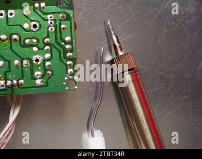 Soldering iron and solder on the electronics repair bench. Focused on soldering iron. Stock Photo