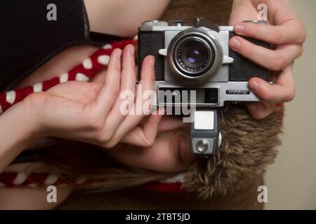 Young Woman holding Camera Sideways in Fun Photographer Pose with Vintage Film Camera Stock Photo