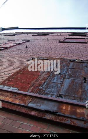 Upward View of Weathered Brick Facade with Rusty Metal Door in Urban Louisville Stock Photo