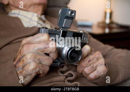 Elderly Hands Holding Vintage Camera in Soft Light Stock Photo