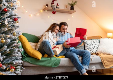 Man surprised with his Christmas present. Young couple during Christmas holidays. Stock Photo