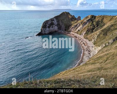 Aerial view of Lulworth Cove with turquoise waves crashing against ...