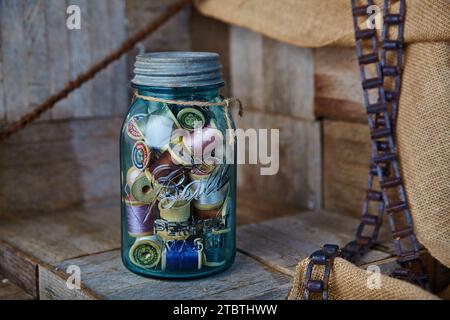 Vintage Sewing Essentials in Blue Mason Jar on Rustic Wooden Surface Stock Photo