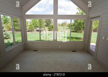 Three Season Room with Large Window Overlooking Lush Backyard in Fort Wayne Stock Photo