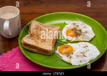 Closeup Image Of Toasted Bread And Sunny Side Up Eggs In Green Plate With Tea Stock Photo