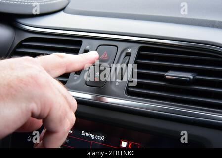 Man pressing red triangle car hazard warning button Stock Photo