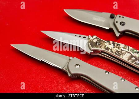 Variety of Folding Knives on Vibrant Red Background in Staggered Formation Stock Photo