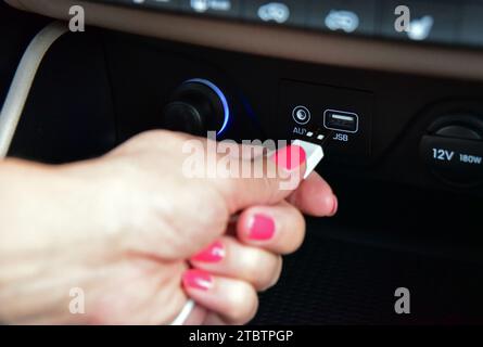 Hand plugging USB cable into the USB port on the car dashboard Stock Photo