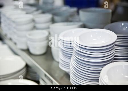 Commercial Kitchen Ceramic Dishware Stacked on Metallic Shelves Stock Photo