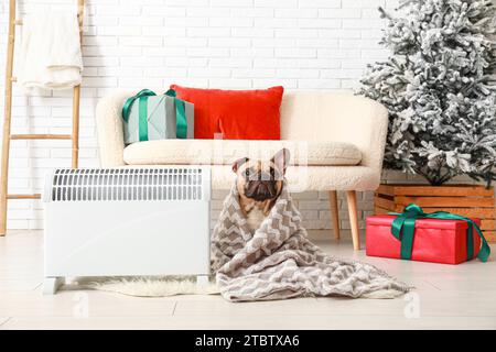 Cute French bulldog with electric heater at home on Christmas eve Stock Photo