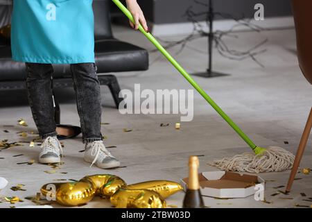 Female janitor sweeping floor in office after New Year party Stock Photo