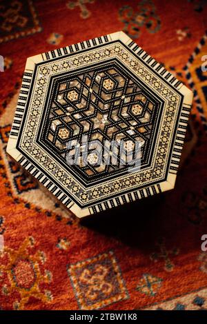 hexagonal middle eastern, moroccan inlaid box design on patterned rug Stock Photo