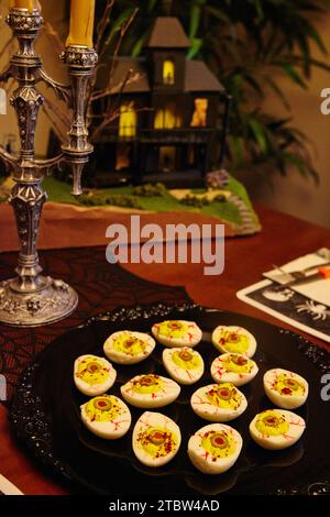 Eerie Halloween Dinner Setup with Eyeball Deviled Eggs and Haunted House Stock Photo