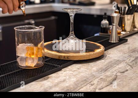 Bartender making smoked whiskey cocktail drink with glass beaker and a cocktail glass full of smoke Stock Photo