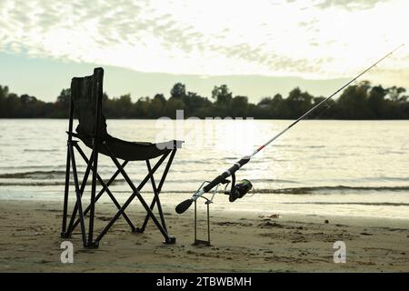 Camping chair with fishing rod at riverside on sunny dayの素材