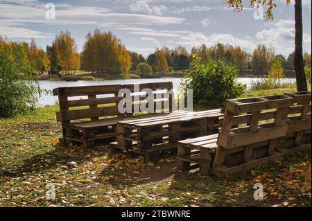 Outdoor furniture made from wood pallets on the shore of a tranquil a lake in autumn Stock Photo