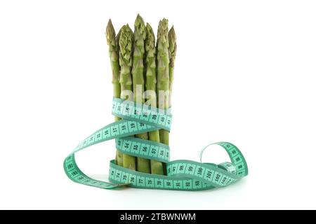 A bundle of green asparagus bound by a measuring tape isolated on white background. The concept of healthy food and slimming Stock Photo