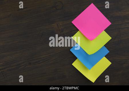 Blank color paper adhesive note stickers with curled corners on rustic board. Free copy space for text Stock Photo