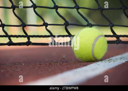 Tennis ball in the net. Ball hitting the tennis net, tennis scene with black net and yellow ball Stock Photo