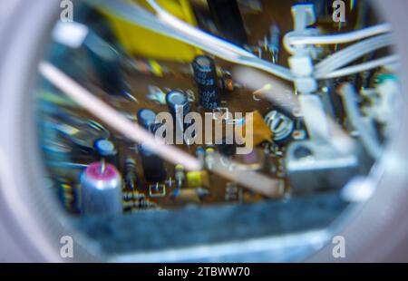 Schwerin, Germany. 28th Nov, 2023. A circuit board with electronic components can be seen under an illuminated workshop magnifying glass. The inner workings of a music system from the GDR company RFT are being repaired in a small workshop for old radios, record players and hi-fi systems. Small electrical appliances from East and West have been restored to working order here for around 34 years. Regular customers with a soft spot for GDR radio technology in particular hand in their devices to the trained radio and television technician. A lack of spare parts Credit: dpa/Ģ����ý Live News Stock Photo