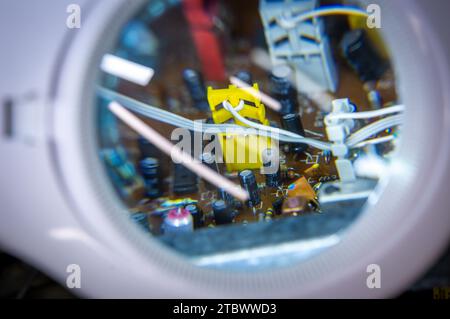 Schwerin, Germany. 28th Nov, 2023. A circuit board with electronic components can be seen under an illuminated workshop magnifying glass. The inner workings of a music system from the GDR company RFT are being repaired in a small workshop for old radios, record players and hi-fi systems. Small electrical appliances from East and West have been restored to working order here for around 34 years. Regular customers with a soft spot for GDR radio technology in particular hand in their devices to the trained radio and television technician. A lack of spare parts Credit: dpa/Ģ����ý Live News Stock Photo