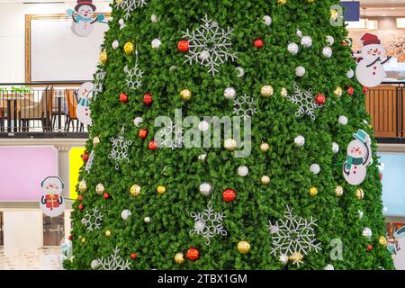 Christmas tree with New Year's toys balls, glowing snowflakes and snowmen inside the building Stock Photo