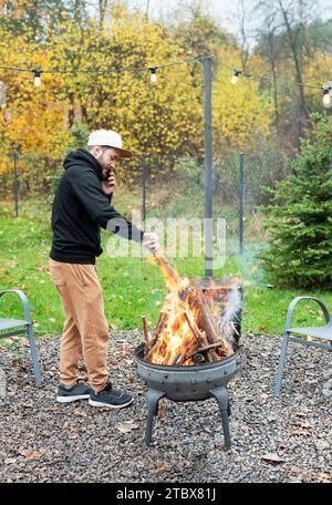 A man lights a barbecue in nature near the house Stock Photo