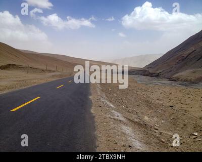 A scenic desert landscape featuring a long, winding road that stretches across a valley and into the distant mountain range Stock Photo