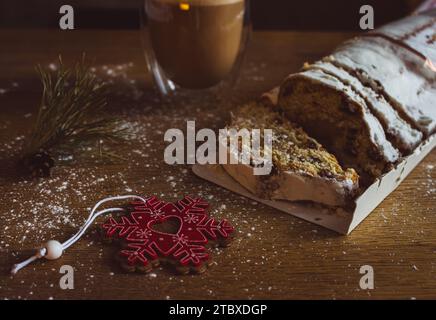 Christmas stollen with coffee cup and decoration toys. Sweet Christmas bread with cacao and powdered sugar. New Year decor. Homemade stollen. Stock Photo