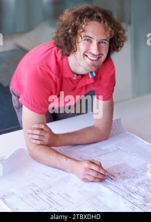 Portrait, happy man and architect on blueprint working on creative project on startup table. Face, designer smile and engineer on drawing, document Stock Photo