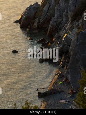 Greece: rocky shore, serene sunset over Aegean Sea. Stock Photo