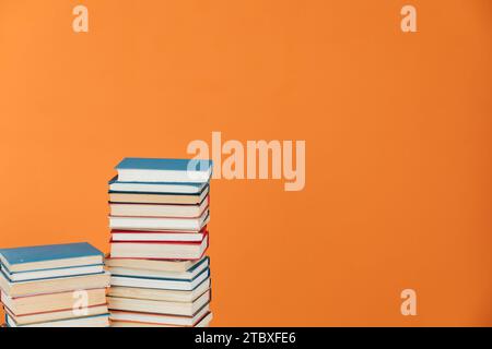 Stacks of educational books in library on orange background Stock Photo